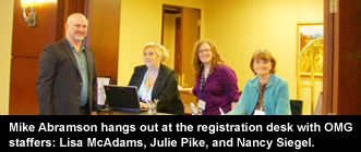 Mike Abramson hangs out at the registration desk with OMG staffers: Lisa McAdams, Julie Pike, and Nancy Siegel.&nbsp;